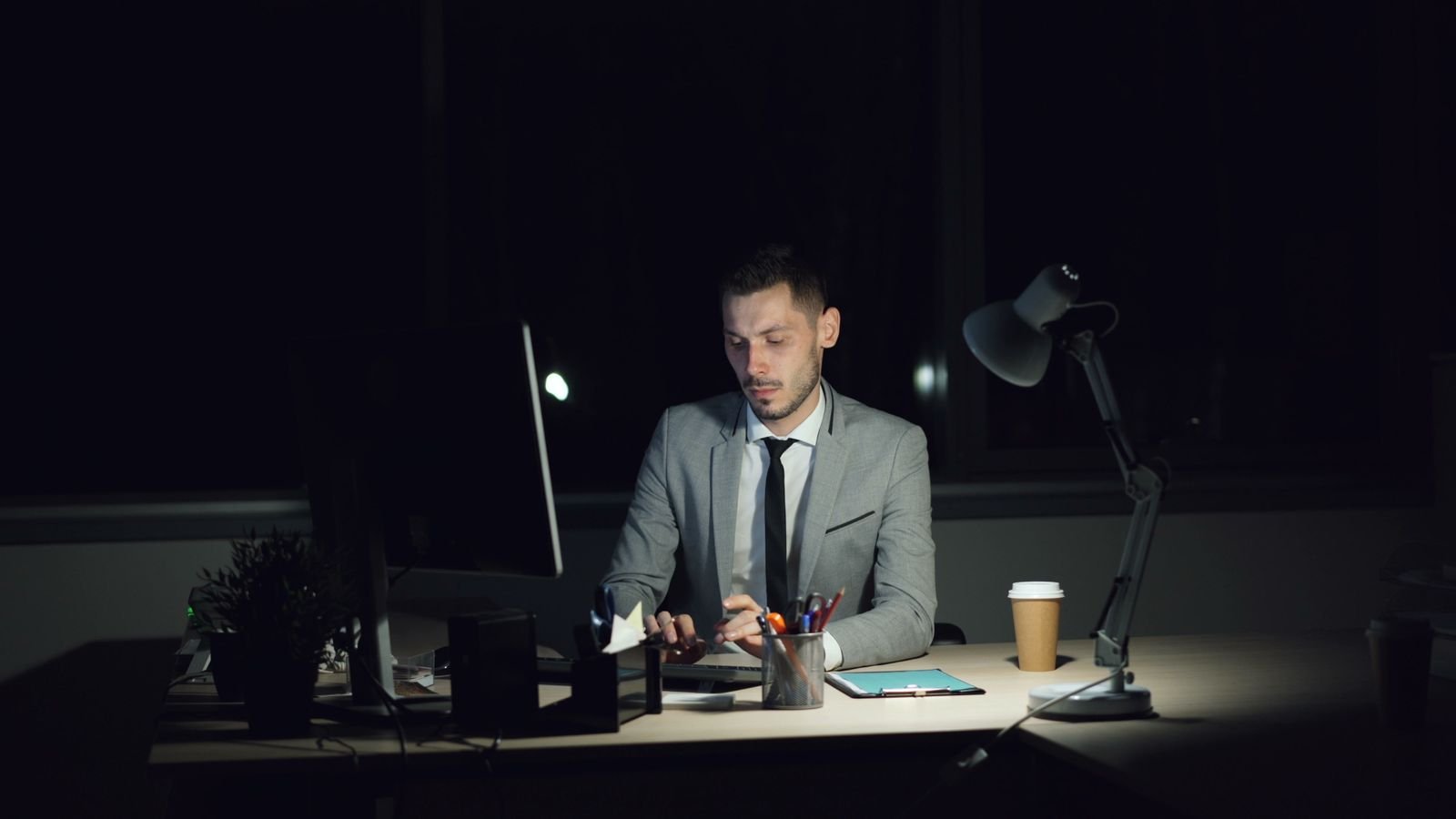 An executive still at his desk late at night, lit only by a desk lamp